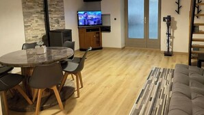 Un salon moderne avec une table à manger ronde, un canapé, un téléviseur et une cheminée.
