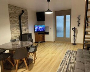 Een moderne woonkamer met een ronde eettafel, een bank, een televisie en een open haard.