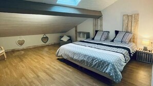 Une chambre avec une lucarne, un plancher en bois, un lit avec une literie à motifs et des décorations murales en forme de cœur.