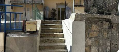 A two-story house with a stone staircase leading to the entrance.