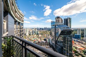 Un edificio de gran altura con fachada de vidrio moderna, vista de un paisaje urbano con diversos edificios y un cielo despejado.