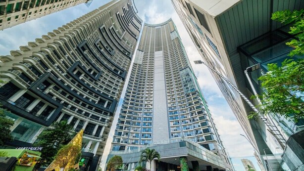 Um edifício alto com fachada curva, várias varandas e fachada de vidro.