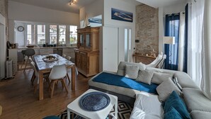 Ein geräumiger Wohnbereich mit einer Couch, einem Esstisch und einer Küche im Hintergrund.