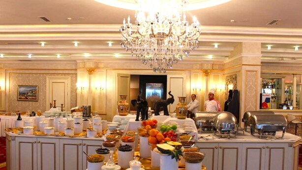 A buffet setup in a hotel lobby with a chandelier, buffet stations, and a bar area. - Modern Hotel - Baku (Baku)