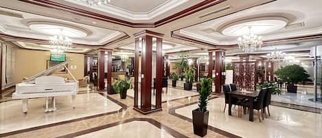 A grand lobby with a grand piano, chandeliers, and a polished marble floor.