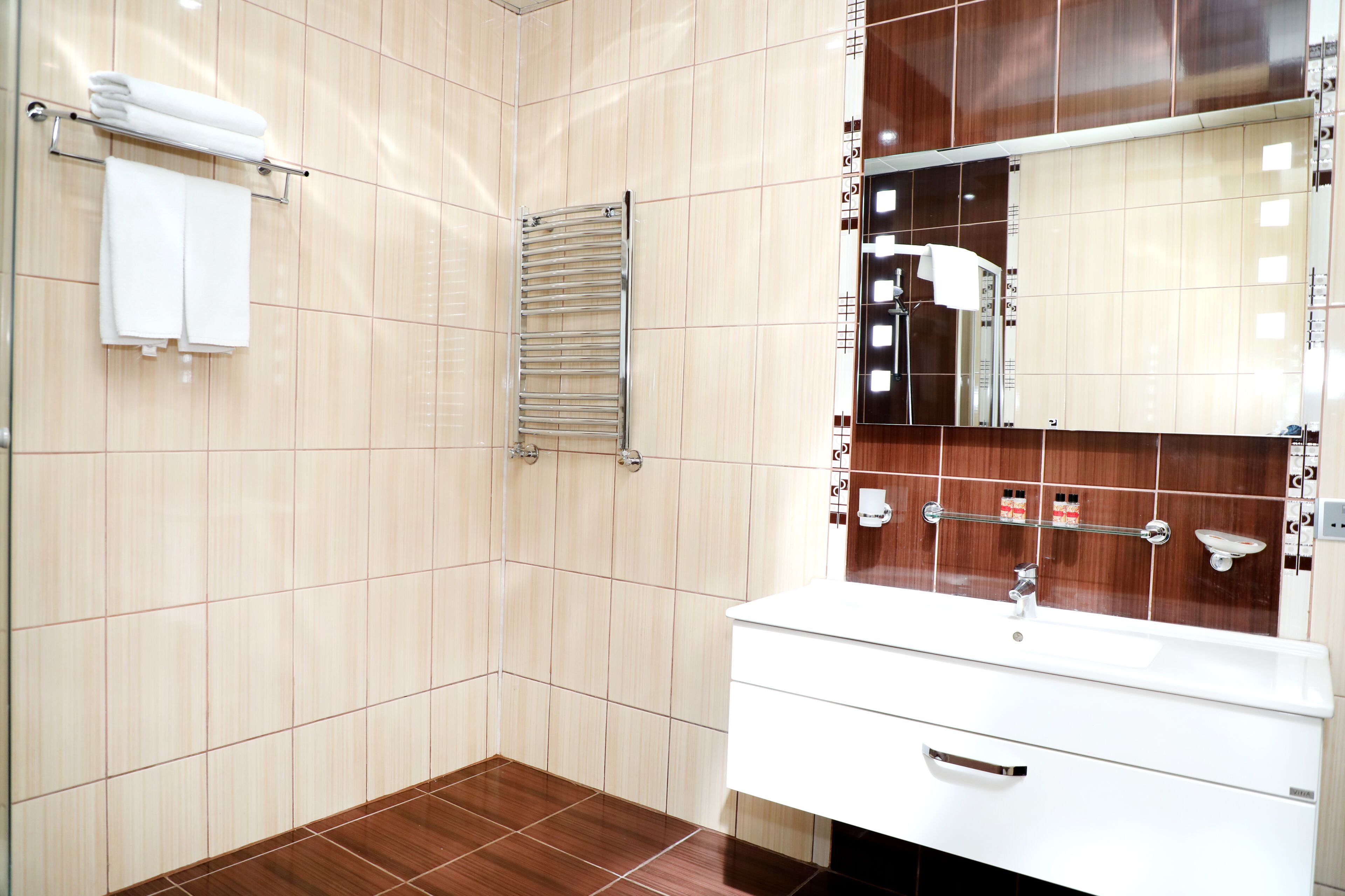 A modern bathroom with a white vanity, a large mirror, and a towel rack.
