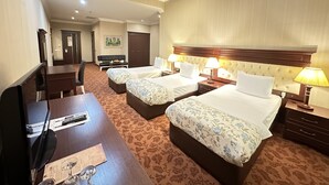 A hotel room with two beds, a desk, a chair, a TV, and a dining table. - Modern Hotel - Baku (Baku)