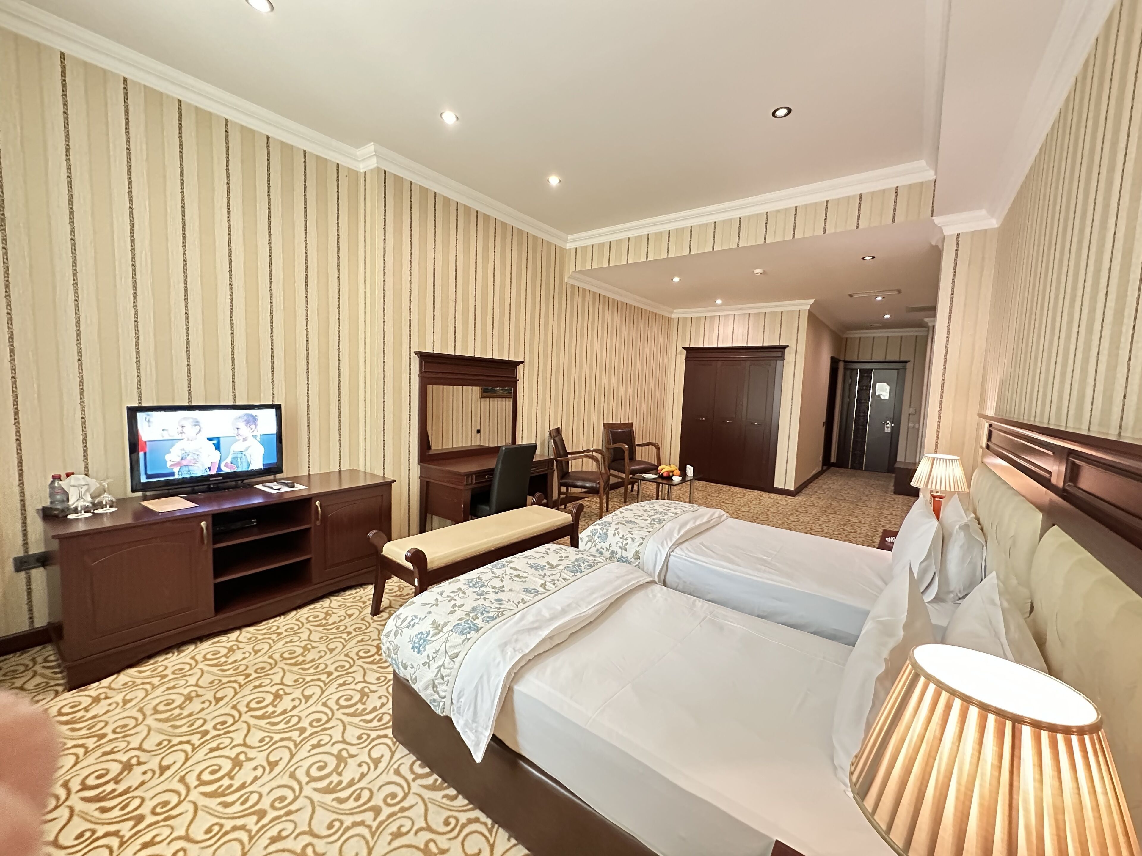 A hotel room with two beds, a television, a desk, and a wardrobe.