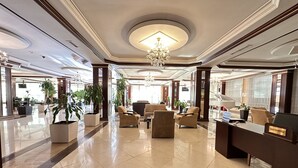 A spacious lobby with a chandelier, comfortable seating, and potted plants. - Modern Hotel - Baku (Baku)