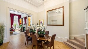 Un coin repas avec une table et des chaises en bois, un grand miroir et un escalier.