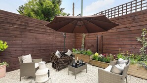 Eine Terrasse mit Korbmöbeln, einer Feuerstelle und einem Holzzaun.