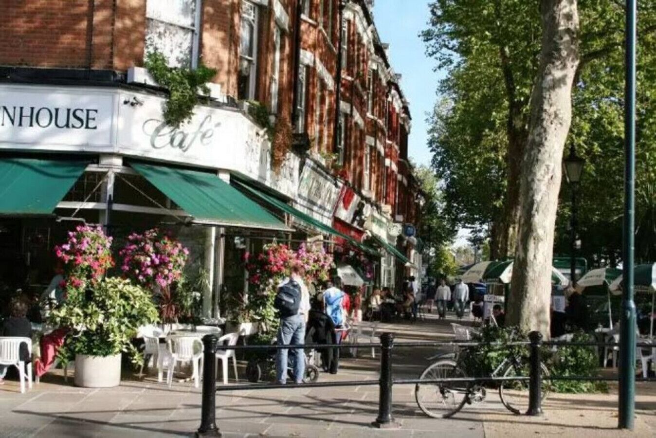A street view of a cafe with outdoor seating, a bicycle parked nearby, and a building with a 'cafe' sign.