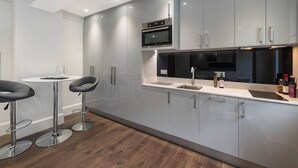 A modern kitchen with grey cabinets, stainless steel appliances, and a white countertop. - Chelsea Apartment | King`s Road, Sloane Sq, Lift & Underground Parking (London)