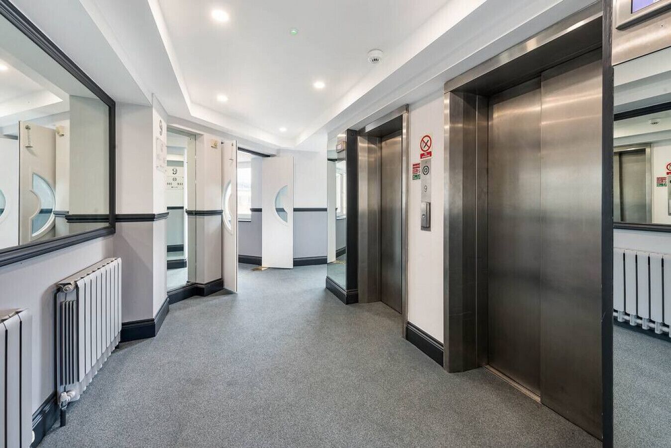 Een modern liftgedeelte met metalen deuren en een vloerbedekking.