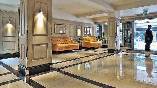 A lobby with two sofas, a polished floor, and a person standing by the entrance. - Chelsea Apartment | King`s Road, Sloane Sq, Lift & Underground Parking (London)