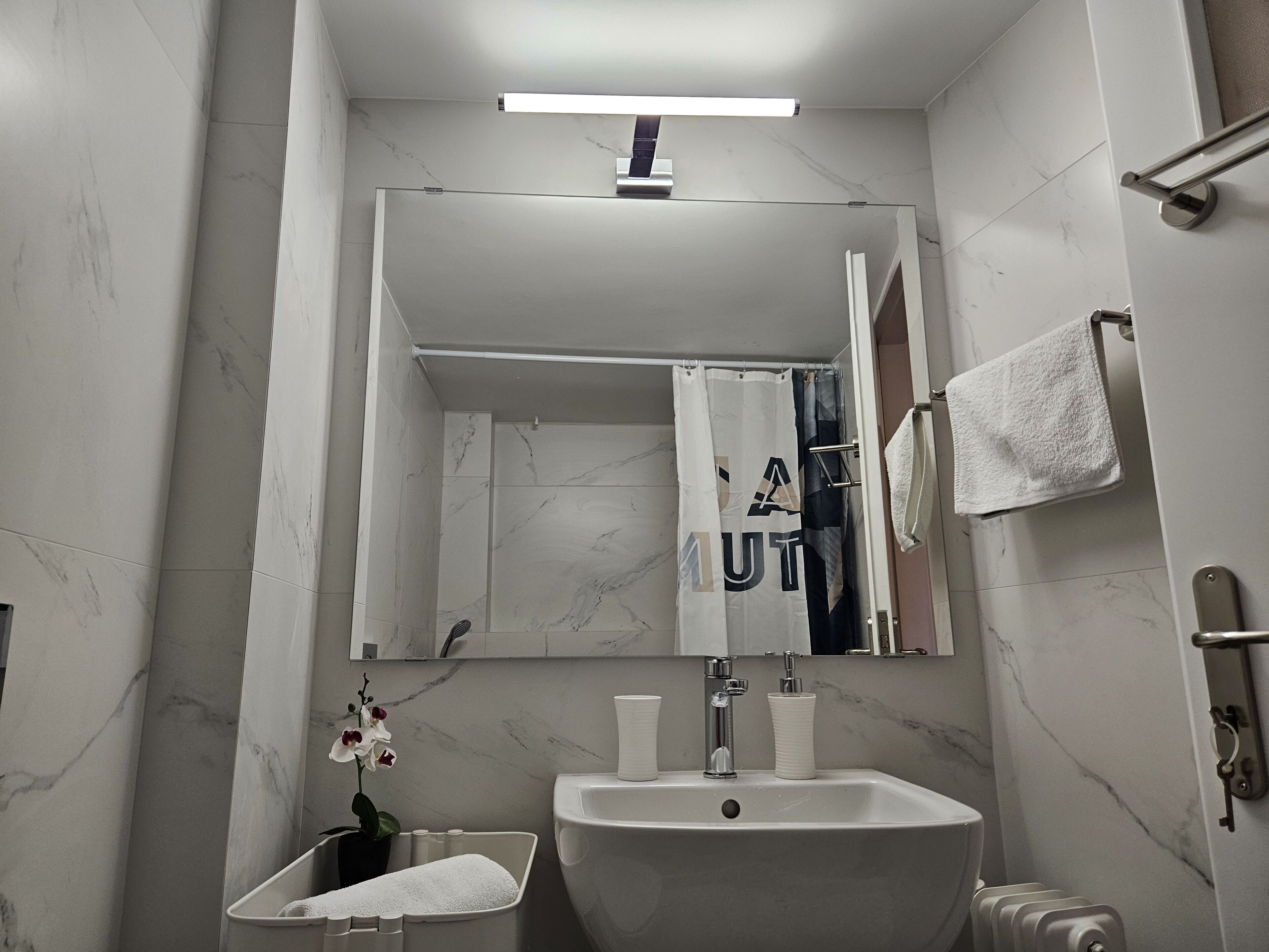 A modern bathroom with a large sink, mirror, and shower curtain.