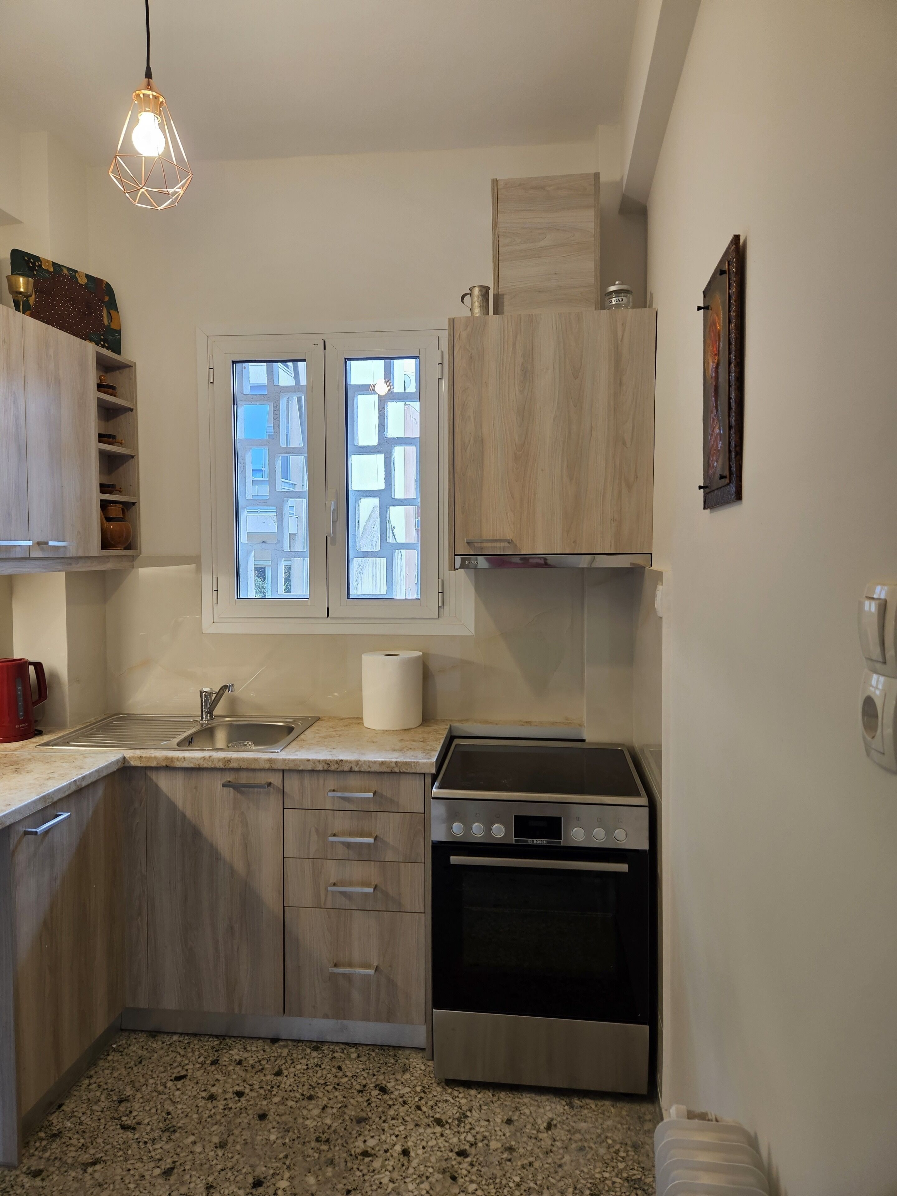 A compact kitchen with a built-in stove, a sink, and wooden cabinets.