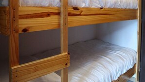 Un lit superposé à deux niveaux, chaque niveau étant équipé d’un matelas et d’un cadre en bois.