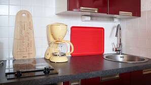 Une cuisine équipée d’une machine à café, d’une planche à découper rouge et d’un tableau de menu en bois.