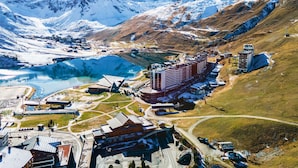 Eine Berglandschaft mit einem großen Gewässer, einem Skigebiet und mehreren Gebäuden, darunter ein Hotel.