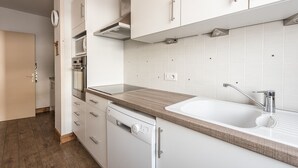 Eine moderne Küche mit weißen Schränken, einer Holz Arbeitsplatte, einem Einbauofen und einem Geschirrspüler.