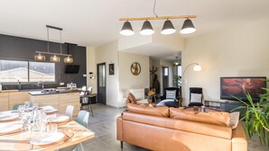 Un espacio moderno para vivir con comedor, sofá, televisor y cocina.