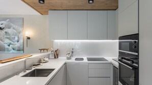 Une cuisine moderne avec des meubles blancs, un four encastré et une machine à café.