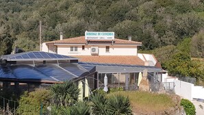 A restaurant with a sign reading "Auberge de Cannedda Restaurant - Grill - Chambres" surrounded by greenery and solar panels. - Auberge de Cannedda (Sari-Solenzara)