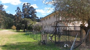 A fenced outdoor area with a building, trees, and a clear sky. - Auberge de Cannedda (Sari-Solenzara)