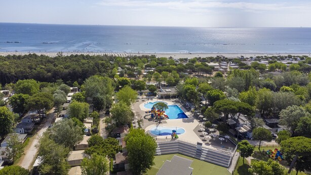 Vue aérienne d’un complexe hôtelier doté d’une piscine, d’une plage et d’une végétation luxuriante.