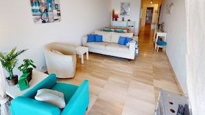 A modern living room with a sofa, armchair, and a dining area with a table and chairs.