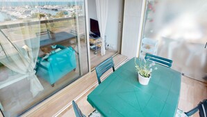 A balcony with a view of boats and water, a table with chairs, and a potted plant.
