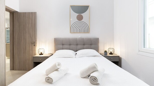 Ein modernes Schlafzimmer mit einem großen Bett, zwei Nachttischen, einer Kopfteil und einem Wandbild.