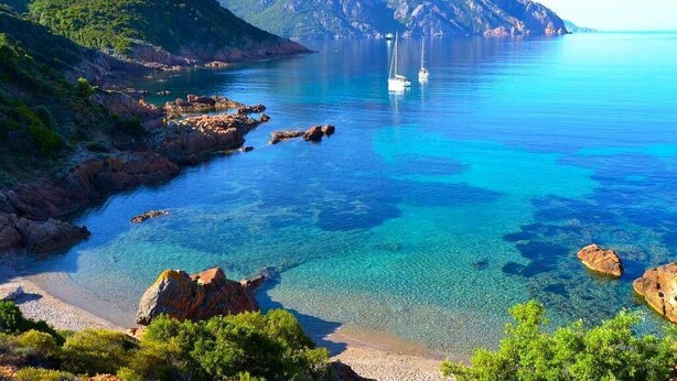 A coastal landscape with clear blue waters, rocky shores, and a mountain in the background. - Spend exceptional holidays in a protected village , by the sea (Osani)