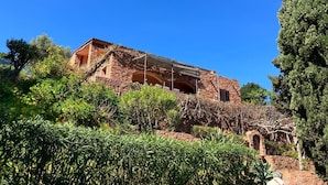 A stone building with a covered patio, surrounded by greenery. - Spend exceptional holidays in a protected village , by the sea (Osani)