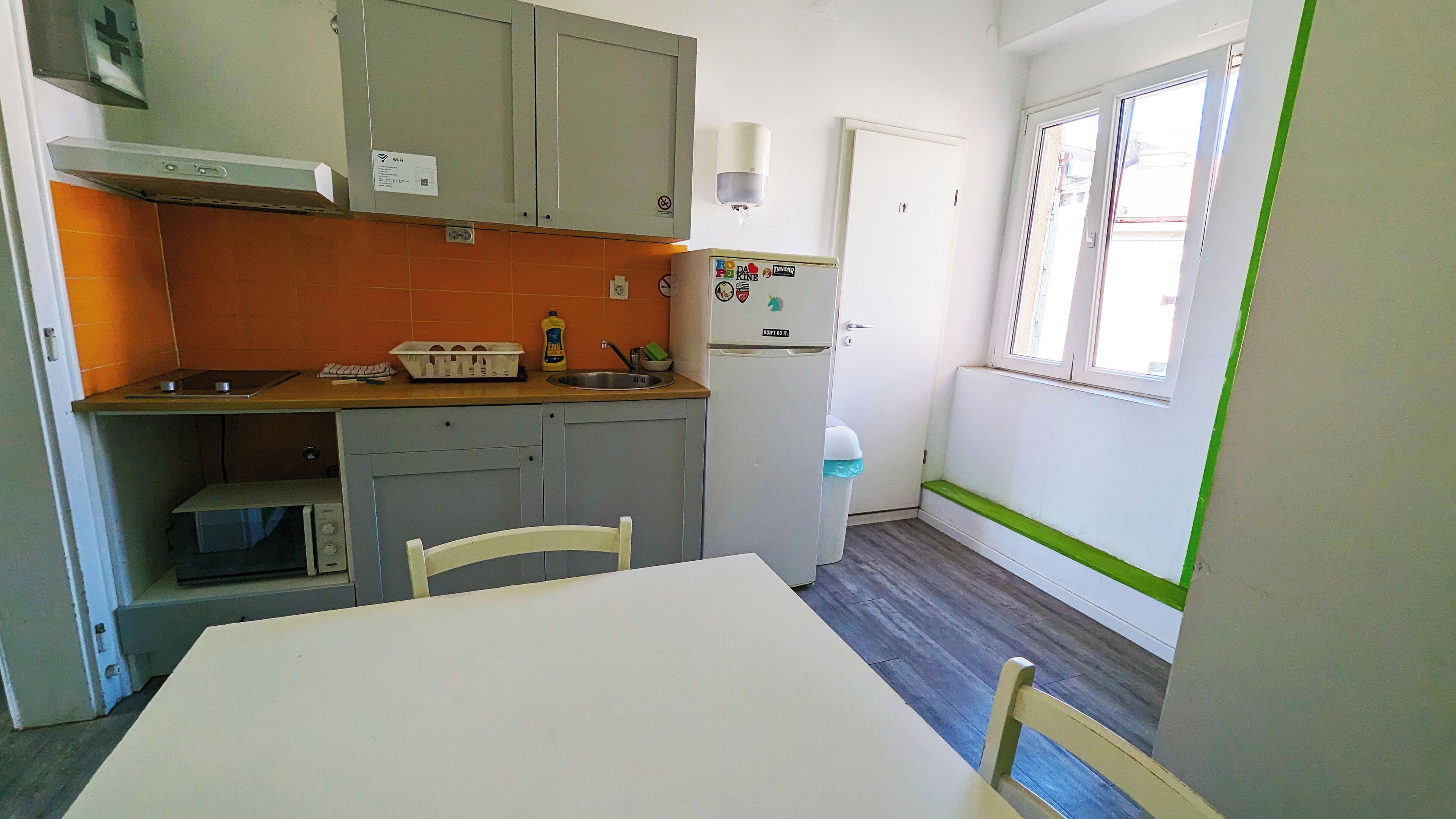 A compact kitchen with a table, chairs, a sink, and a refrigerator.