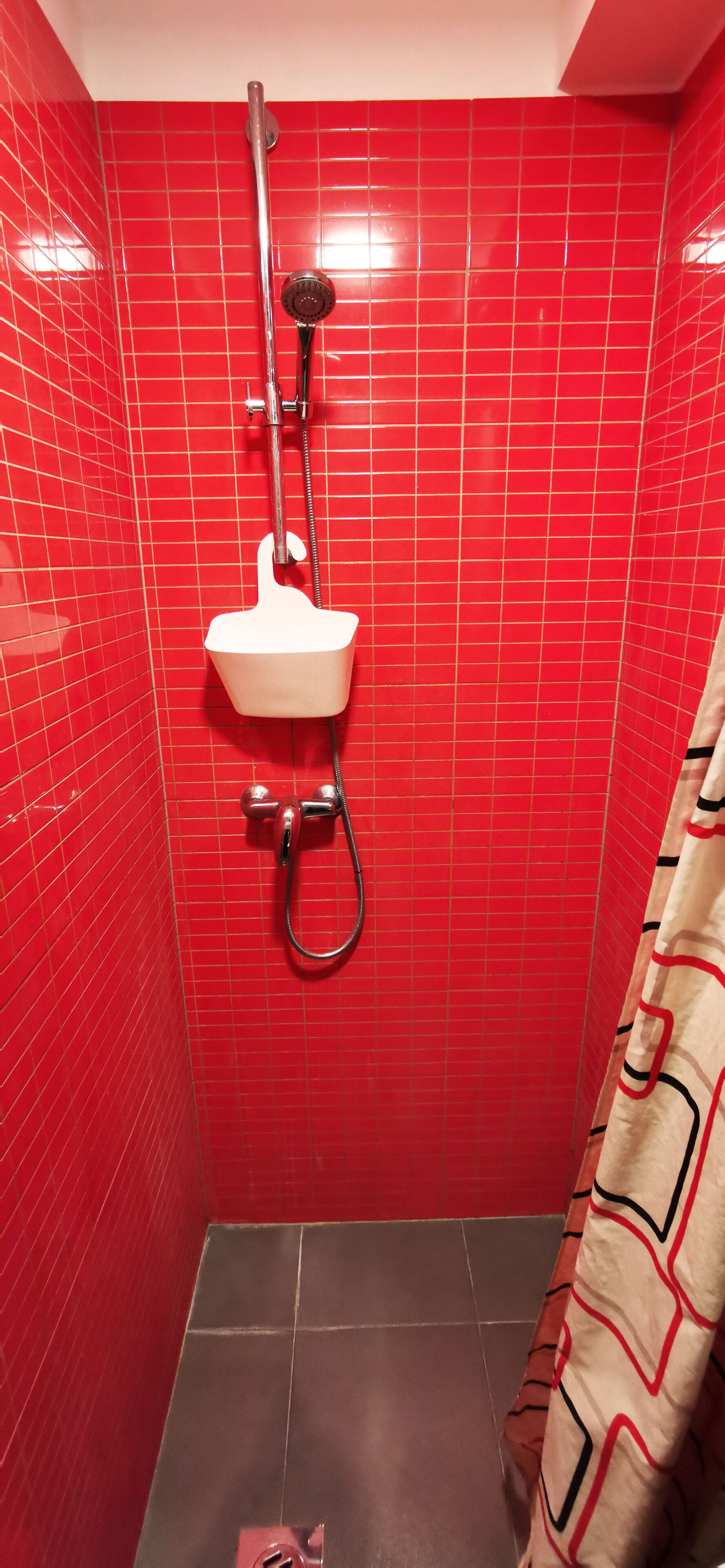 A bathroom with red tiled walls, a white sink, and a shower.