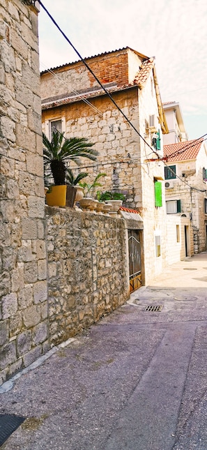 A narrow street with stone buildings, a potted plant, and a metal gate. - Croparadise Hostel (Split)