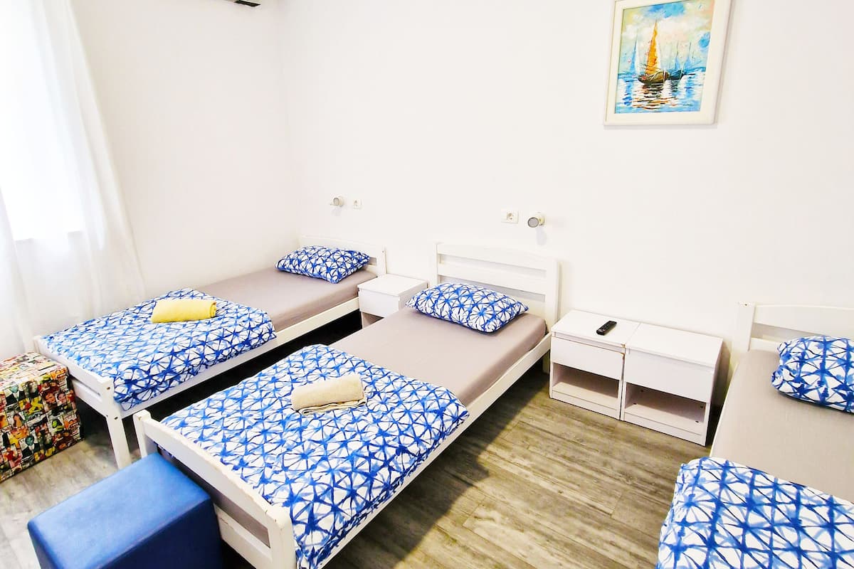 A room with two single beds, a small desk, a chair, and a storage unit.