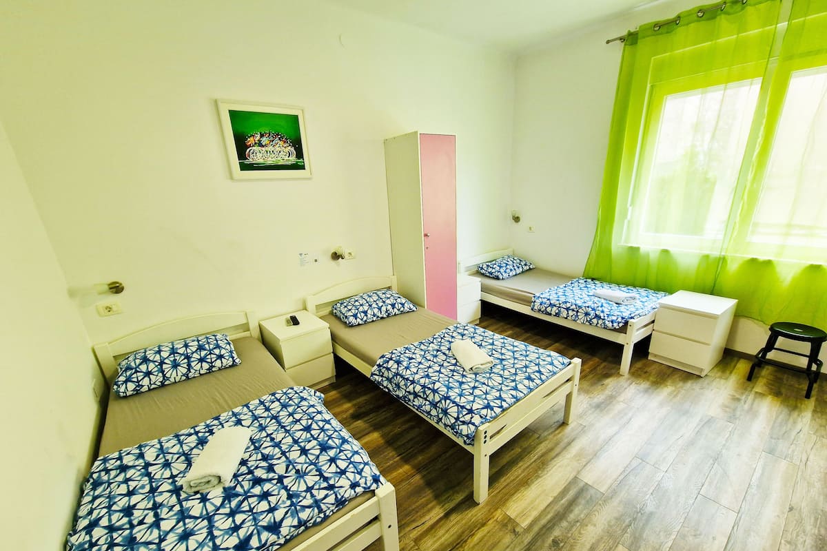 A room with three single beds, a desk, a chair, and a wardrobe.
