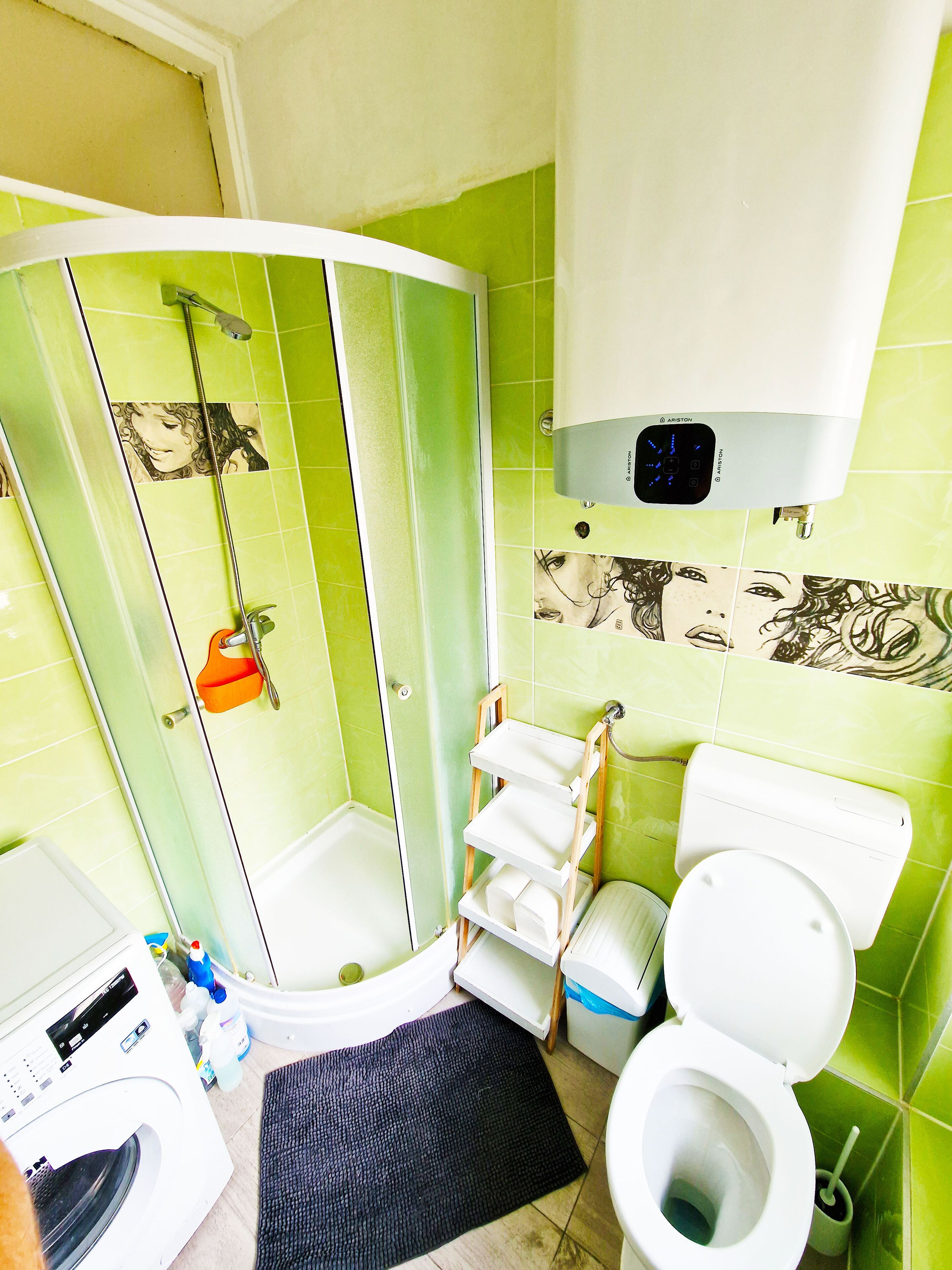 Baño con ducha, inodoro y lavadora.