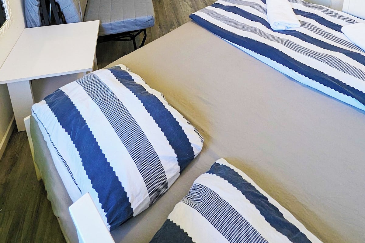 A hotel room with a bed, a desk with a computer, a chair, and a television.