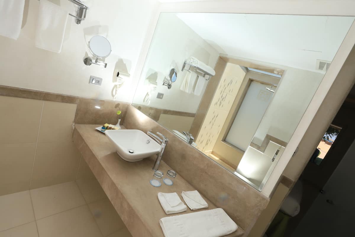 A bathroom with a sink, mirror, and towel rack.