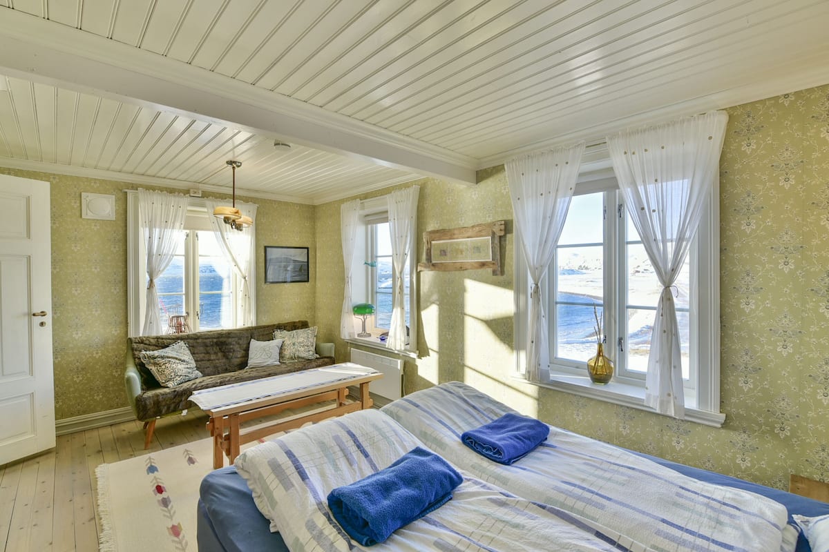 Ein Schlafzimmer mit zwei Betten, einem Schlafsofa, einem Tisch und Meerblick.