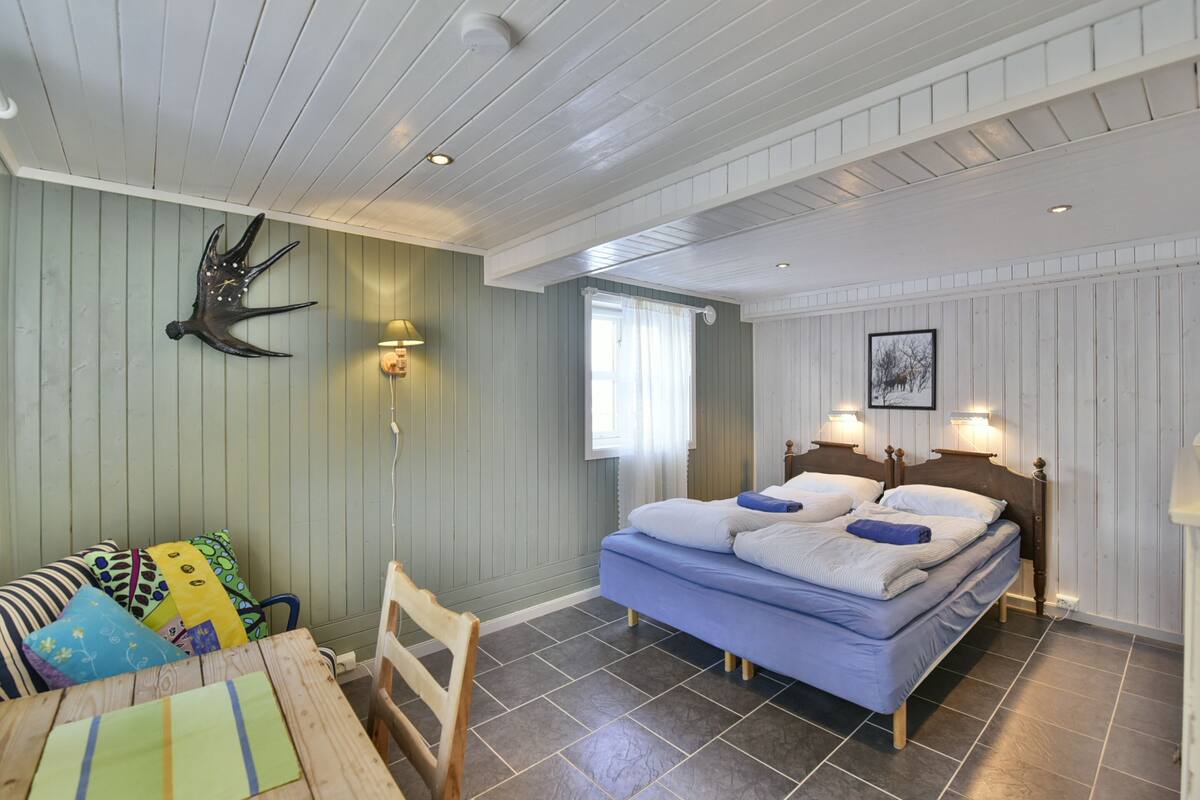 Ein Schlafzimmer mit Bett, Stuhl, Tisch und Wanddeko.