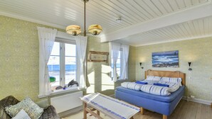 Une chambre à coucher avec un lit, un banc, un canapé et une fenêtre avec des rideaux.