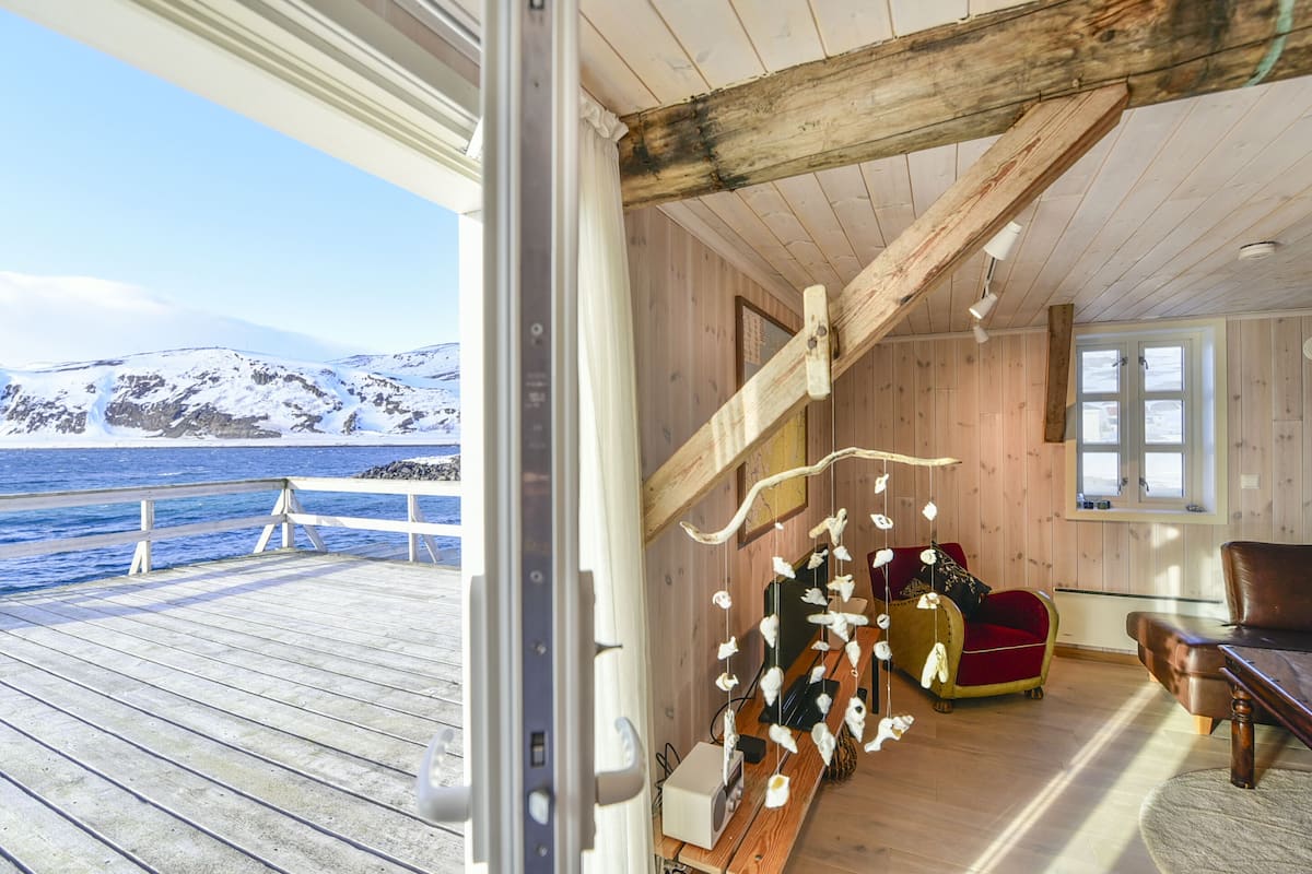 Ein Holzinterieur mit Blick auf das Meer und die Berge.