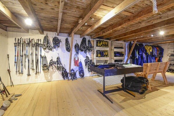 A ski equipment room with racks of skis, snowboards, and boots. - Kongsfjord Arctic Lodge (Berlevag)