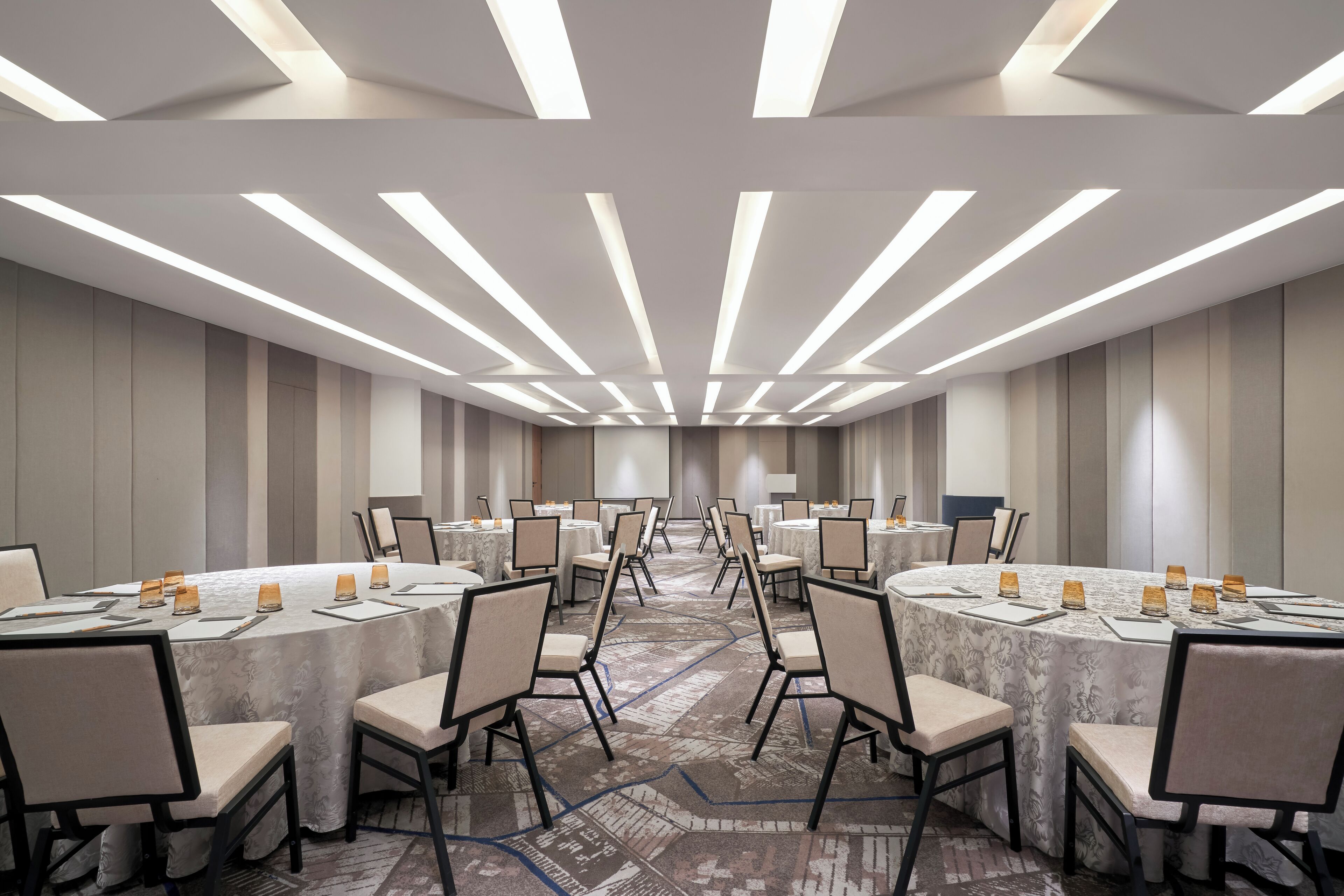 A conference room with round tables, chairs, and a carpeted floor.