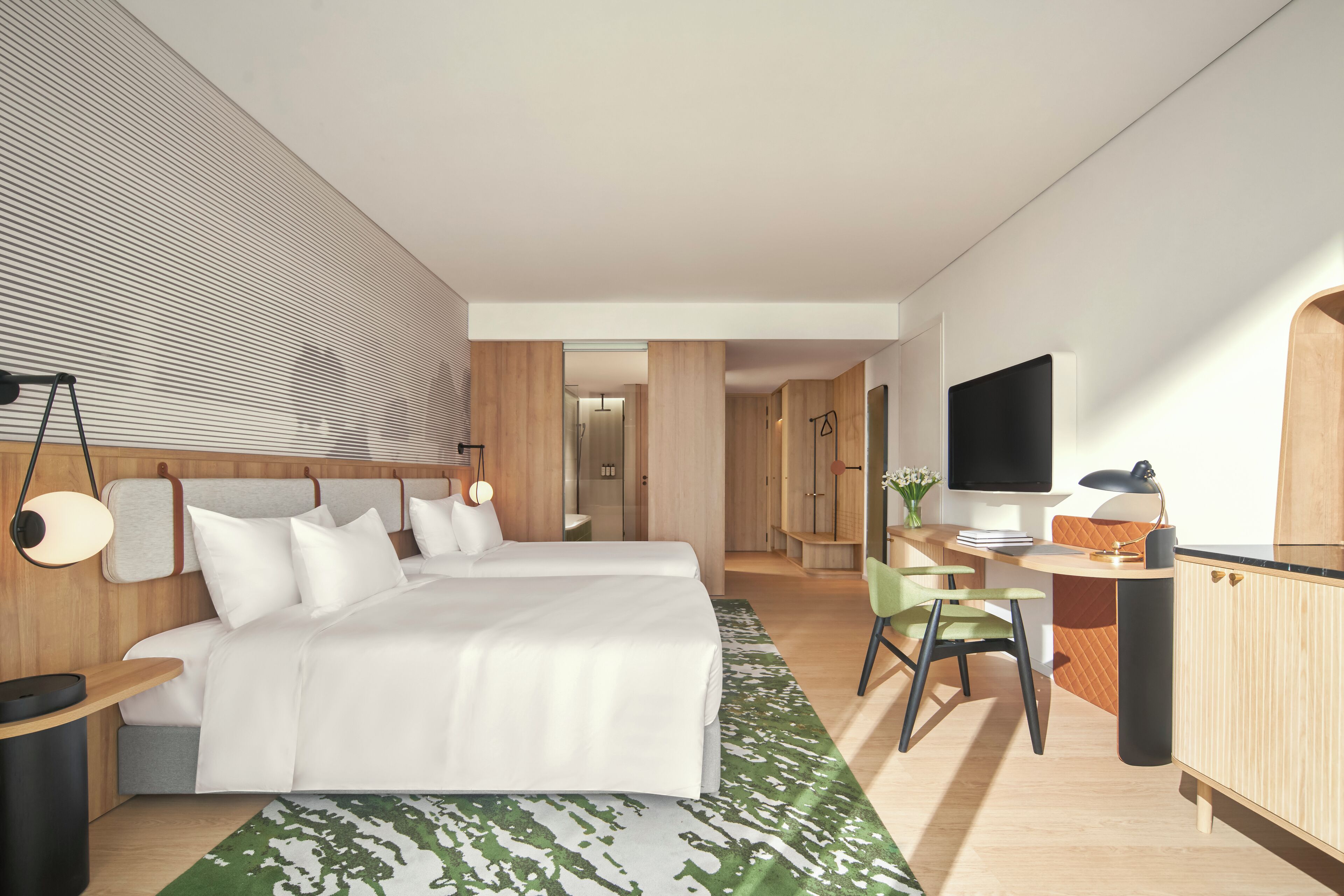 Une chambre d’hôtel moderne équipée de deux lits, d’un bureau, d’une chaise et d’un téléviseur.
